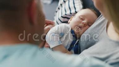婴儿睡在慈爱的父母手上。 从后面看。 观念----父母照顾，坚强的家庭
